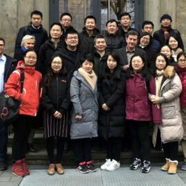 Besucherinnen und Besucher aus Shanghai stehen vor dem Schulgebäude