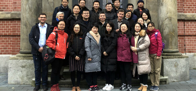 Besucherinnen und Besucher aus Shanghai stehen vor dem Schulgebäude