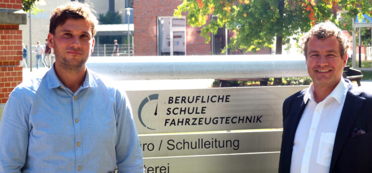 Herr Garbelmann und Herr Wranik vor dem Schullogo