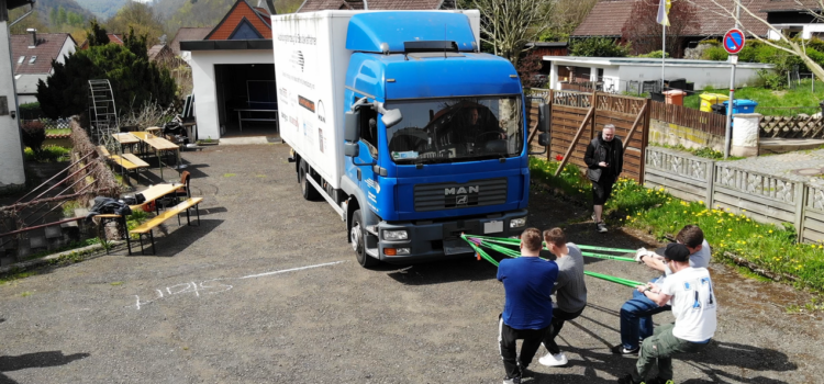 Schüler ziehen mit Leinen einen LKW vorwärts als Wettbewerb.